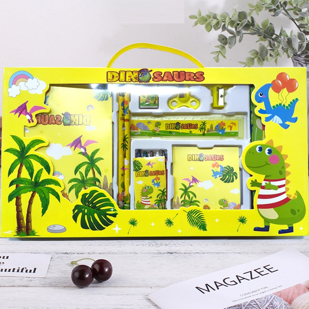 Dinosaur-themed stationery set in a yellow box on a white surface with greenery in the background.