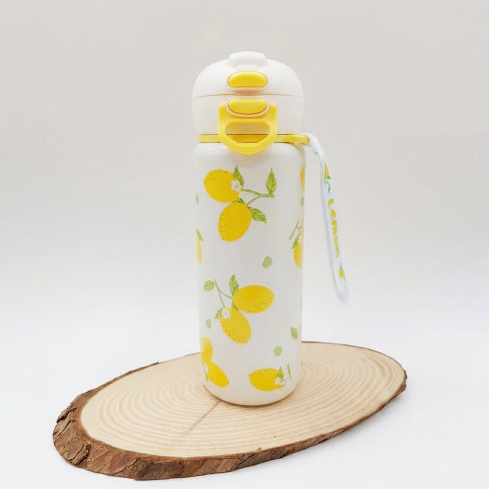 A white insulated water bottle with a yellow lemon print, featuring a flip-top lid with yellow accents and a matching carrying strap, displayed on a round wood slice against a light gray background.